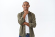 © Cookie Studio - Very interesting. Portrait of intrigued african-american man, touch chin squinting and smiling, nod in approval, see something satisfying, positive feedback, like product, feel pleased