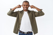 © Cookie Studio - Portrait of annoyed, displeased complaining african-american man, irritated over loud noise, shut ears and grimacing discomfort, neighbours started repairment works, white background