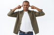 © Cookie Studio - Portrait of annoyed, stressed african-american man shut ears, grimacing and pouting, bothered by loud neighbour or annoying sirent, hear terrible sound or noise, white background