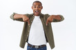 © Cookie Studio - Portrait of excited handsome african-american man talking about big news, great discounts, pointing fingers down, look happy camera beaming smile from amazement and joy, white background