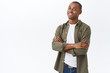© Cookie Studio - Portrait of smart, professional african-american man, standing white background with hands crossed on chest, confident pose, smiling satisfied, promote company service, delivery or customer support