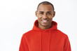 © Cookie Studio - Close-up portrait of young african-american adult man in red hoodie, smiling happy, staying healthy at home, order new game console for self-distancing quarantine days, white background