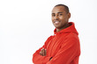 © Cookie Studio - Close-up portrait of young successful african-american adult man in red hoodie, cross arms on chest turn head to camera with satisfied smile, looking confident and reliable, white background