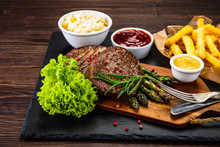 Barbecue Beef Steak French Fries And Vegetables On Black Stone