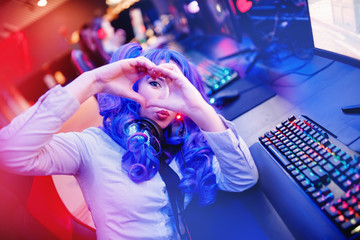 Streamer beautiful woman shows heart sign with hands professional gamer playing online video games computer, neon color