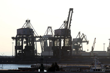  Taranto merchant port at sunset. Silhouette of harbor cranes. Puglia, Italy