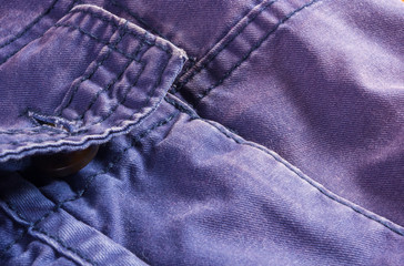 clothing items stonewashed cotton fabric texture with seams, clasps, buttons and rivets, macro