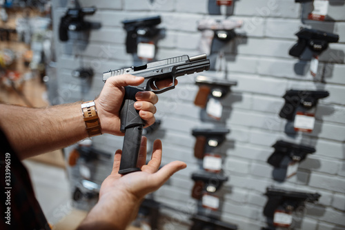 Man choosing new handgun in gun shop Tableau sur Toile