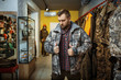 © Nomad_Soul - Man trying on uniform at showcase in gun shop