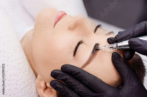 Fotomural Beautiful young girl with long eyelashes tweezing her eyebrows in a beauty salon