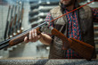 © Nomad_Soul - Man cleans rifle barrel at counter in gun shop