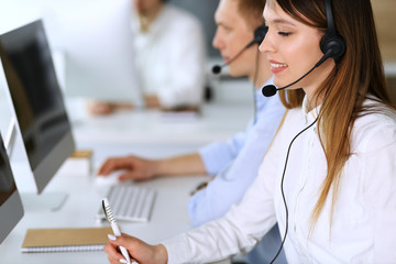 Call center. Group of diverse operators at work. Focus on beautiful asian woman in headset at customer service office. Business concept