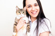 © Yuliya Timofeeva - A woman holds a domestic adult cat in her arms and looks into the frame. The owner and the cat on a white background. Pets.