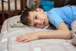 © Юлия Буракова - Child boy lies on the bed with a displeased face, is sick. Home quarantine. Virus. flu. Bed rest