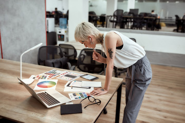 new project. young stylish blonde tattooed female designer making some sketches and working with col