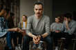 © Roman - young caucasian man sit in the center during therapy session in support group for anonymous alcoholics, tired of drinking alcohol. healthcare concept