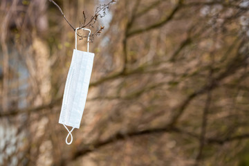 Wall Mural - Coronavirus COVID-19 and healthcare concept. Medical mask hanging on a tree branch in spring