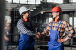 © Тарас Нагирняк - Two young builders in working uniform and helmets ready for a work, handshake.