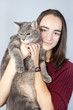 © Natalya Antoshchenko - Beautiful smiling brunette holds in her arms a large striped gray cat