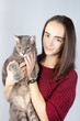 © Natalya Antoshchenko - Beautiful smiling brunette holds in her arms a large striped gray cat