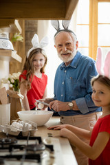 Wall Mural - Mirthful man cracking eggs and smiling stock photo