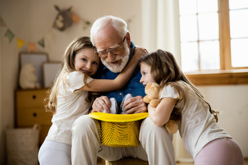 Wall Mural - Elderly magician with his cute granddaughters stock photo