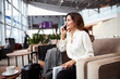 Cheerful lady having phone conversation in departure lounge