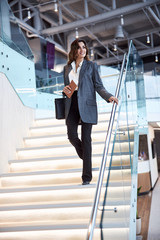 Wall Mural - Cheerful young woman walking down the stairs