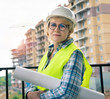 © Luca9257 - A female construction worker is on a construction site wearing a helmet and vest.