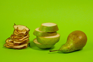 Dried pear chips, closeup shot on a green background. Background for a healthy diet.