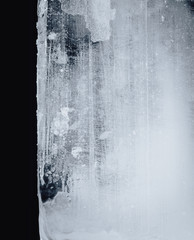 Wall Mural - Blue toned transparent ice block, on white surface, isolated on black background.