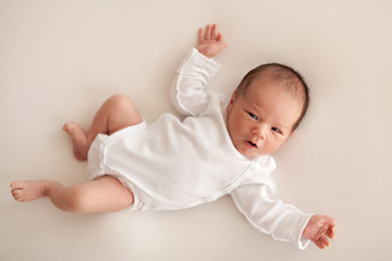 Newborn baby boy in white body on bed