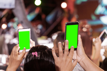 Wall Mural - Hands of audience crowd people taking photo with mobile smart phone with green screen in party concert.