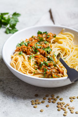 Vegetarian lentils bolognese pasta with parsley in white dish. Healthy vegan food concept.