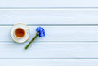 Summer tea party. Cup near cornflowers bouquet on blue wooden background top-down copy space