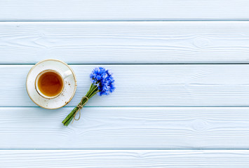 Wall Mural - Summer tea party. Cup near cornflowers bouquet on blue wooden background top-down copy space