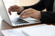 © fizkes - Businessman sit at desk typing on laptop, financial stats with charts lying on desk, hands device close up. Analyst working using pc develops insights, create business strategy. Office routine concept