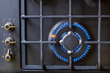 Fototapeta Miasta - Gas burner on black modern kitchen stove. kitchen gas cooker with burning fire propane gas.
