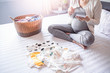 © Have a nice day  - close up of pregnant woman writing on notebook sitting on bed with baby clothing in a basket and on the bed. resting and relaxing in the bedroom, wearing stretcher pants and cardigan with sun shine