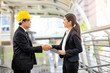 © Have a nice day  - asian businesswoman   a businessman shaking hands in a greeting or a business agreement, holding smart tablet device smiling joyfully with a hardhat, within an urban city district in the background ..