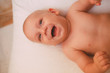 © Артем Коноплянко - a newborn baby is lying in bed, smiling and playing with a toy