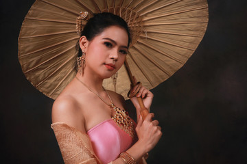 Beautiful Thai woman in traditional dress costume holding an umbrella on black background, Thailand, portrait