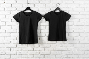 Wall Mural - Black t-shirt hanging on a hanger against brick wall, front view