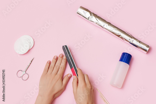 Woman hands removes nail polish on pink background. Canvas