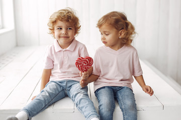 Sticker - Children with candy in a studio. Little girl with her brother. Boy in a pink t-shirt