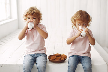 Sticker - Children in a studio. Little girl with her brother. Boy in a pink t-shirt. Chold with cookies and milk.