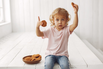 Wall Mural - Child in a studio. Little girl with a cookies. Girl in a pink t-shirt