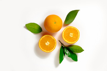 Wall Mural - Close up image of juicy organic whole and halved oranges with green leaves & visible core texture, isolated white background, copy space. Macro shot of bright citrus fruit slices. Top view, flat lay.