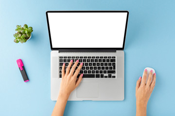 Woman’s hands working on laptop with blank screen. Office desktop with accessories. Top view