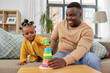 © Syda Productions - family, parenthood and people concept - happy african american father and baby daughter playing with toy blocks at home